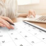 Business Scheduling. Unrecognizable Woman Working On Laptop And Checking Calendar At Workplace