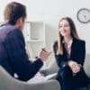 happy businesswoman in suit giving interview to journalist in office