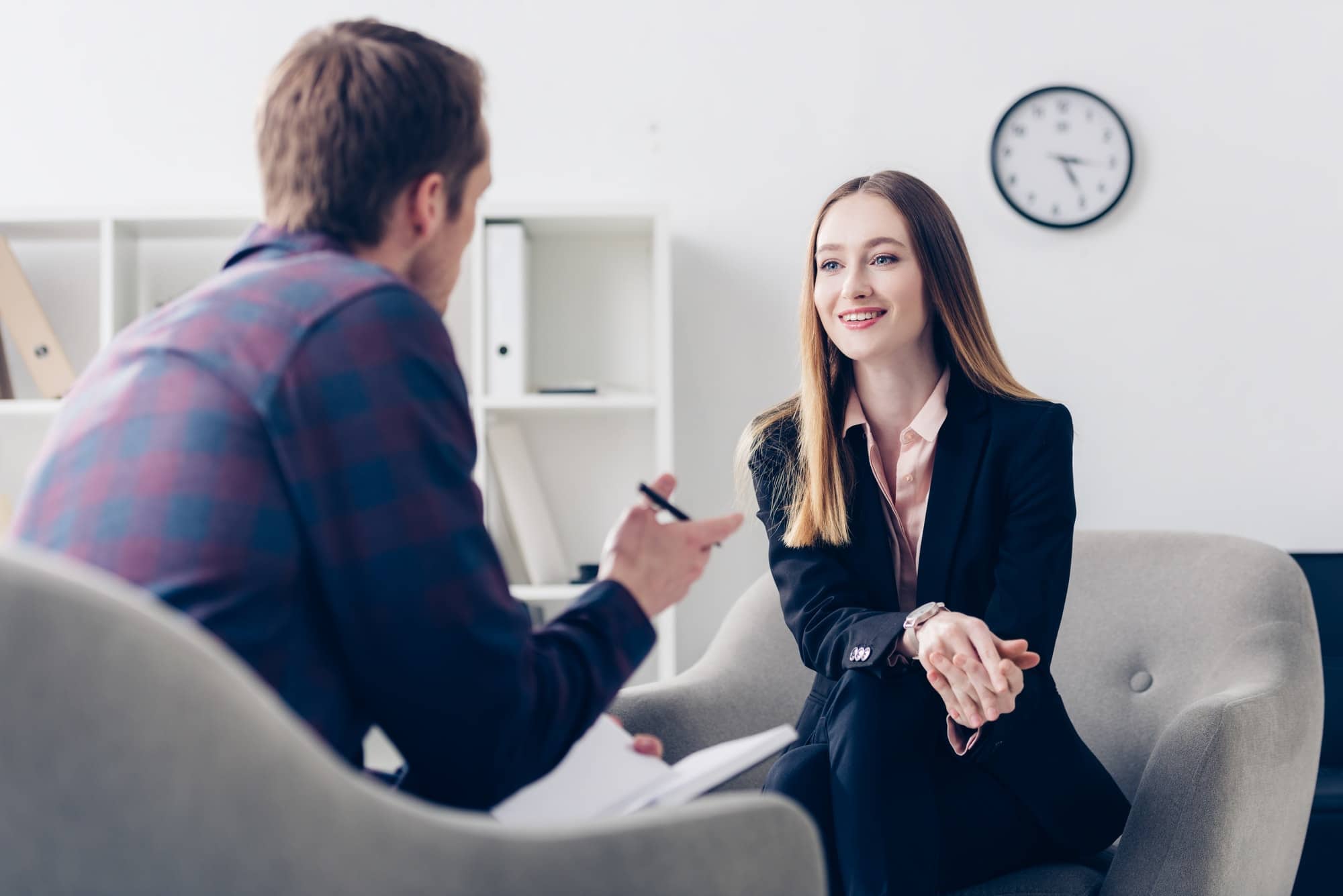 happy businesswoman in suit giving interview to journalist in office