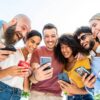 Diverse teenage students using digital smart mobile phones on college campus