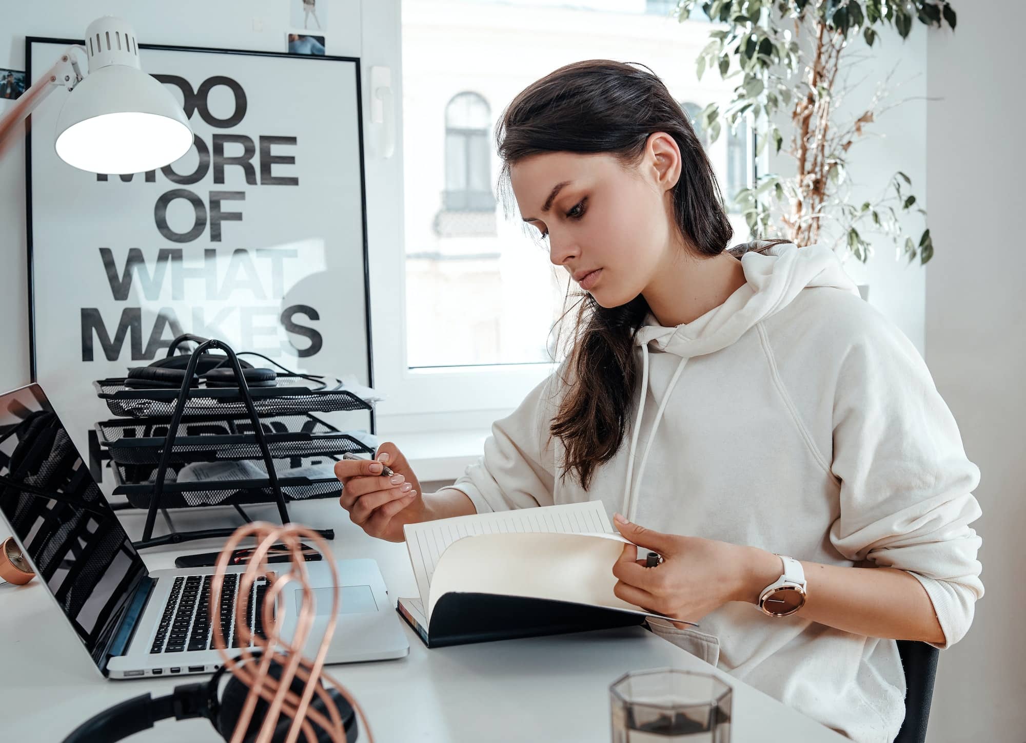 Young businesswoman writes on notebook sitting at table