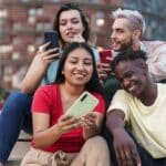 Latin and African American friends sharing social media content on smart phone