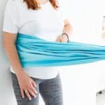 Pregnant woman in white t-shirt doing exercises with doula at home indoor