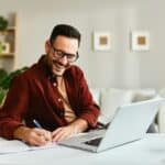 Young business man working at home with laptop and papers on desk