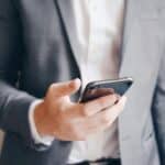 Midsection of a businessman holding his mobile phone, texting or preparing a business call