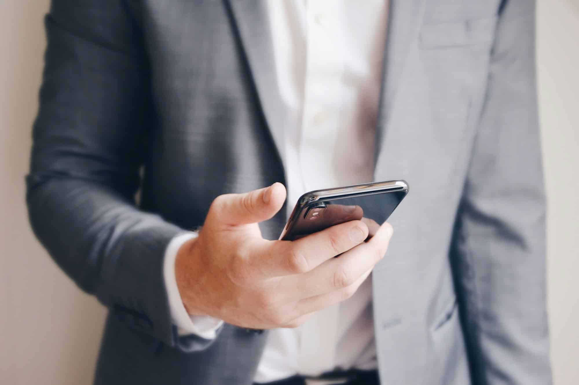 Midsection of a businessman holding his mobile phone, texting or preparing a business call