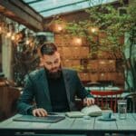 Businessman using business planner and a laptop in a cafe