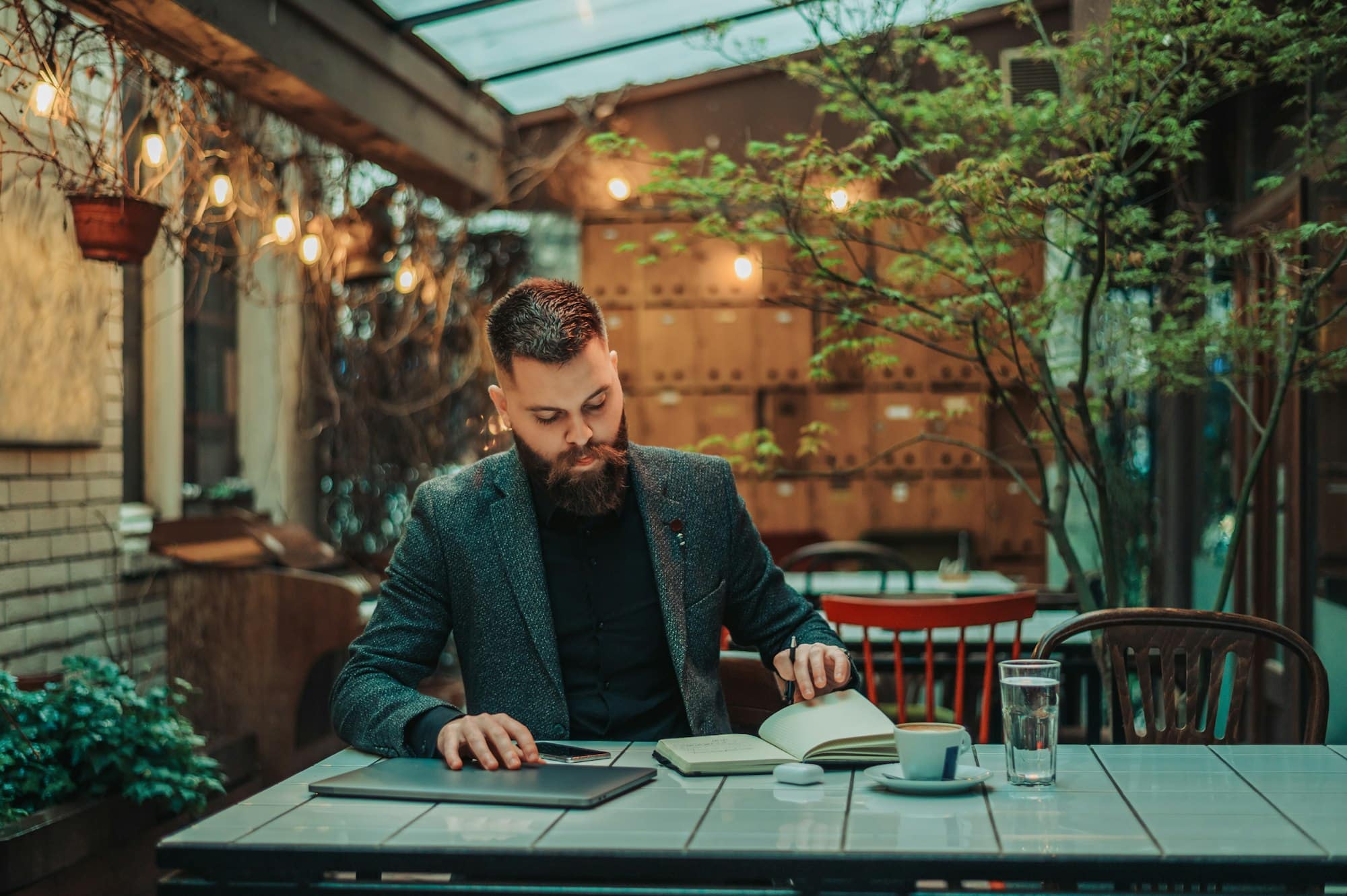 Businessman using business planner and a laptop in a cafe