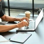 Cropped shot of male worker hands typing on laptop computer, typing email or surfing internet