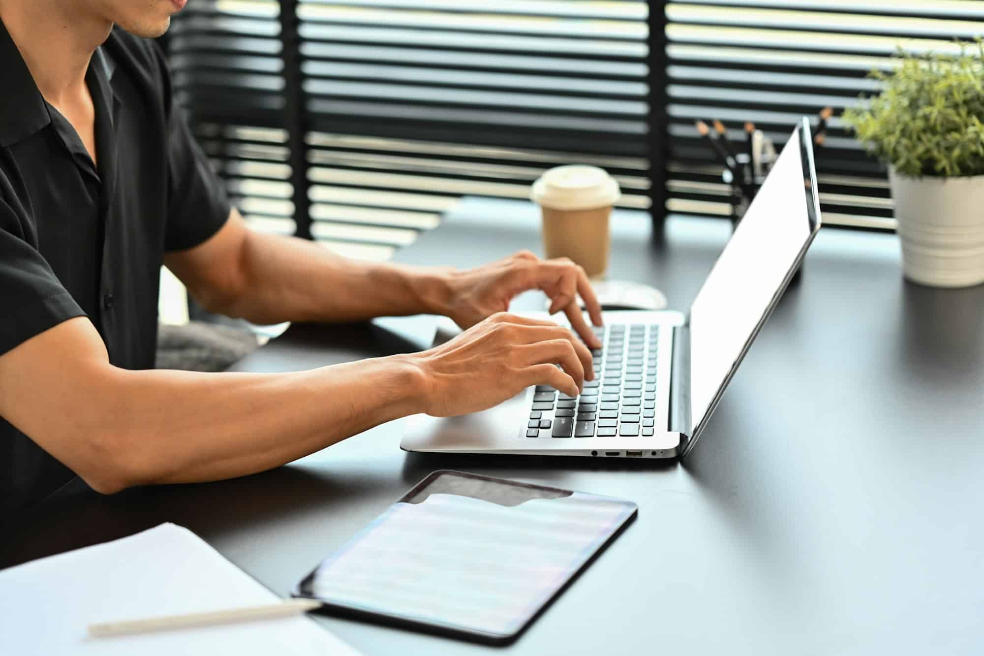 Cropped shot of male worker hands typing on laptop computer, typing email or surfing internet