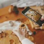 Woman holding phone and taking photo of gingerbread christmas cookies. Instagram photo