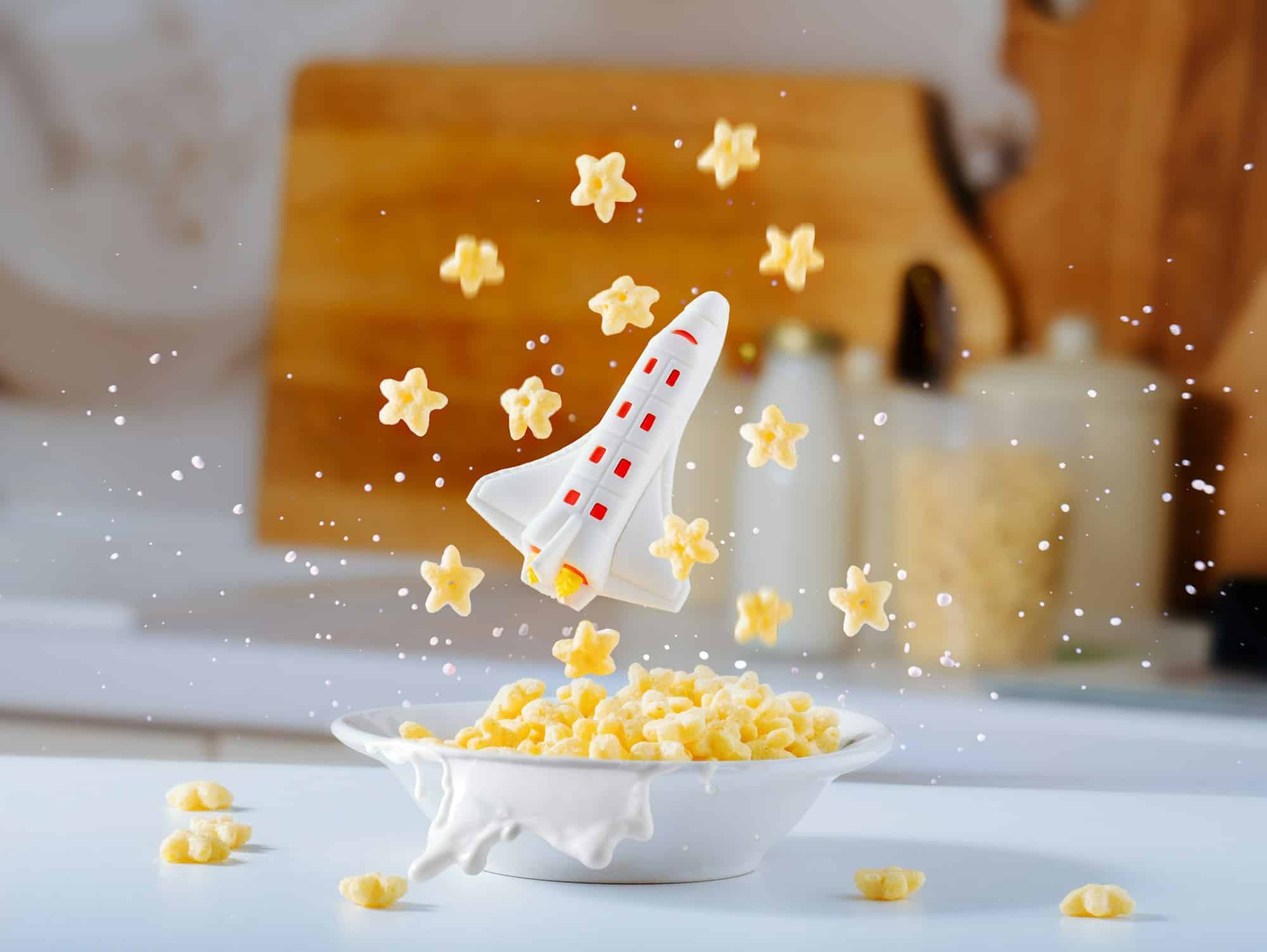 Small space rocket takes off from breakfast plate with cornflakes and milk.