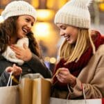 Happy women friends are shopping for presents at Christmas. People holiday sale shopping concept